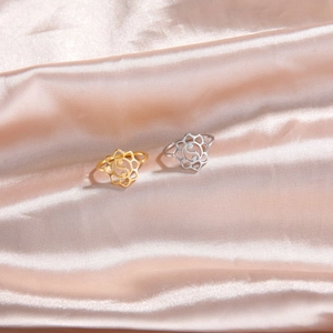 Detail view of hollow lotus Tai Chi rings in gold and silver finish on silk fabric