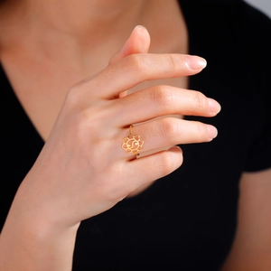Detailed close-up of a gold lotus tai chi ring with hollow geometric patterns on a finger