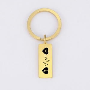 Detailed macro of gold rectangular keychain with heart rate pulse design and initials