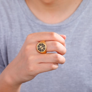 Dettaglio ravvicinato dell'anello Bagua in acciaio dorato indossato sul dito