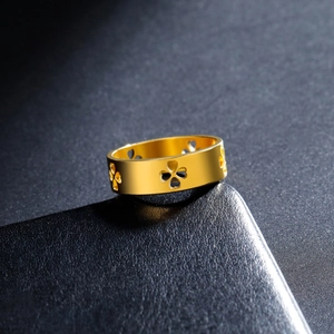 Polished gold clover heart ring with cut-out design on a dark textured background
