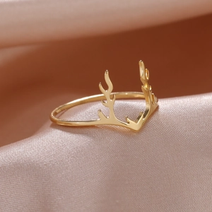 18K vergoldeter Edelstahl Rentier Geweih Ring auf weichem rosa Seidenstoff liegend