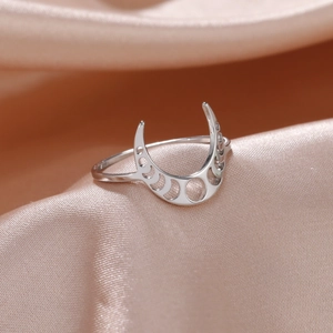 Dettaglio macro dell'anello lunare argento con intagli su tessuto di raso color champagne