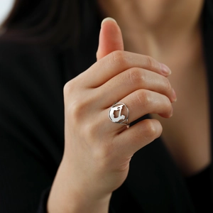 Polished stainless steel ring with yoga silhouette cut-out design worn on model's finger