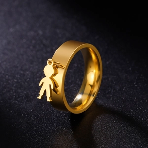 Polished gold stainless steel ring with a hanging boy pendant on a black textured base