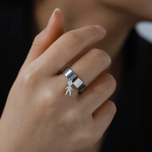Polished stainless steel ring with a small boy pendant hanging on the wide silver band