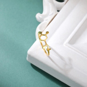 Detailed close-up of golden chemical molecule ring on minimalist white stone frame