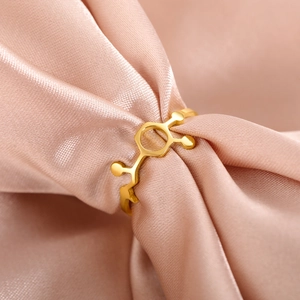 Macro shot of gold molecular structure ring resting on luxurious pink silk fabric