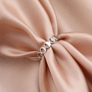 Polished silver crescent moon phase open ring displayed on elegant champagne silk fabric