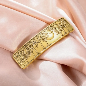 Close-up of golden vintage alloy hair clip with forest and moon embossed pattern