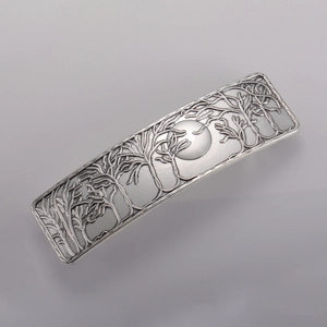 Detail view of silver hair clip featuring embossed forest and moon landscape pattern