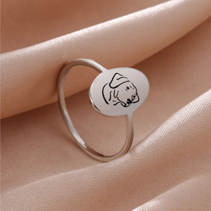 Macro detail of silver stainless steel dog engraved oval ring on satin background