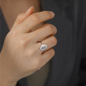 Close-up of a silver stainless steel yoga symbol ring worn on a finger