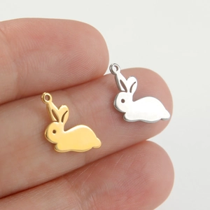 Cute rabbit pendant accessories in gold and silver stainless steel shown on a fingertip