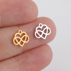 Gold and silver stainless steel infinity heart pendants shown on a fingertip for scale