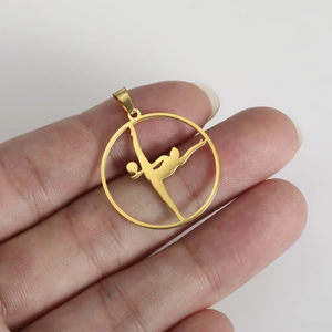 Detailed close-up of a gold stainless steel gymnastics silhouette pendant on a hand