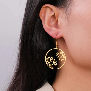 Detail view of golden stainless steel lotus cut-out earrings on a model showing size