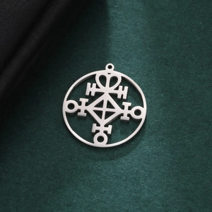 Polished stainless steel circular hollow pendant with geometric rune design on dark textured background