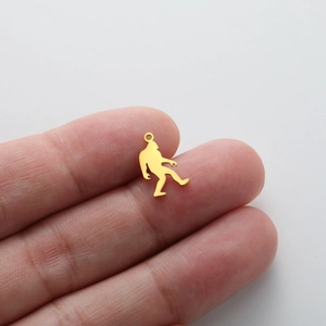Macro shot of a brushed gold Bigfoot charm being held to show the actual product size