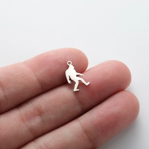 Macro shot of a tiny Bigfoot silhouette pendant in polished stainless steel on a fingertip