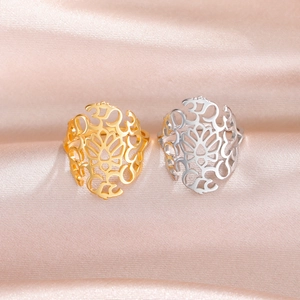 Gold and silver stainless steel Om lotus rings on a soft pink satin textured background