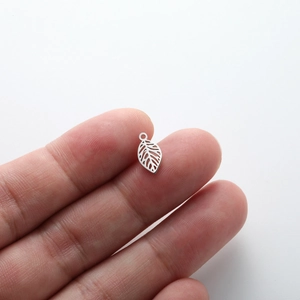 Gros plan d'un pendentif feuille évidé tenu par les doigts montrant les détails