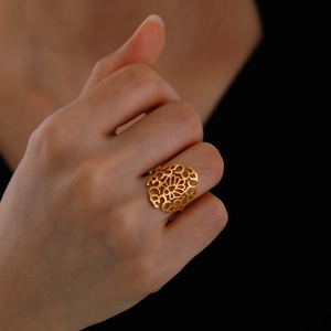 Detailed view of a gold-plated titanium steel ring with intricate hollow floral patterns