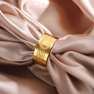 Macro shot of 10mm gold Celtic knot stainless steel ring on luxury satin fabric