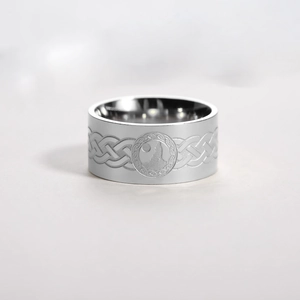 Macro detail of engraved wolf howling at the moon on wide silver steel band ring