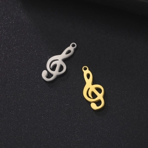 Detailed view of polished gold and silver treble clef music note charms for DIY jewelry