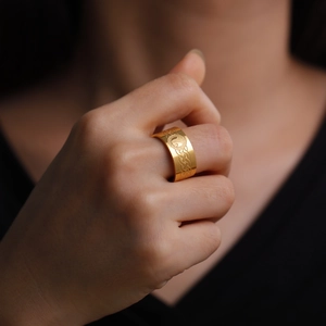 Macro detail of 18K gold stainless steel ring with relief mountain and moon patterns