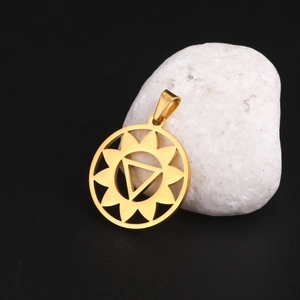 Détail du pendentif ajouré en or 18K avec motif soleil sur un fond de pierre blanche