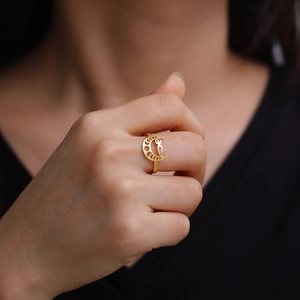Close-up of a gold hollowed moon phase ring on a hand with minimalist lunar design