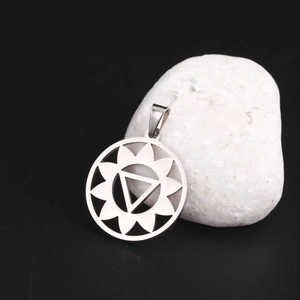 Vue macro du pendentif mandala lotus yoga en or 18 carats sur galets blancs fond noir