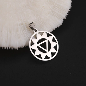 Vue macro d'un pendentif soleil ajouré en métal argenté avec motif géométrique triangle