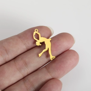 Detailed view of a gold figure skating athlete pendant held by hand for scale