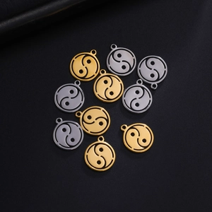 Macro view of gold and silver Tai Chi Yin Yang pendants on black leather surface