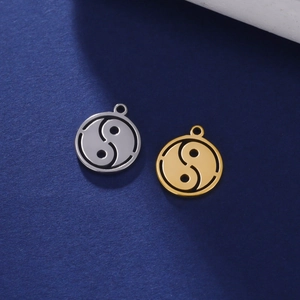 Macro detail of gold and silver stainless steel Yin Yang pendants on blue background