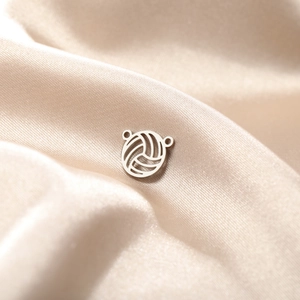 Macro view of a stainless steel volleyball charm with a hollowed design on silk fabric