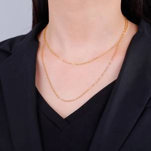 Detail of elegant gold-toned stainless steel cross chain layered on a model's neck