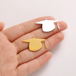 Macro shot of gold and silver graduation cap charms held in hand for scale