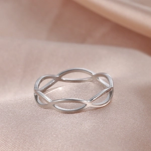 Detailopname van een zilveren infinity-ring op luxe roze zijden achtergrond