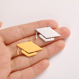 Polished stainless steel graduation cap charms in gold and silver held in hand