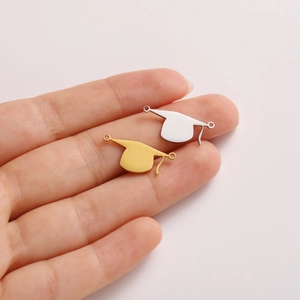 Close-up of gold and silver graduation cap charms for DIY jewelry held in hand
