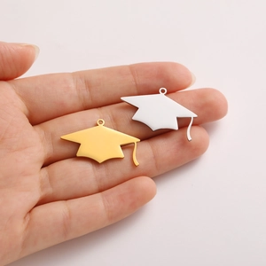 Polished gold and silver graduation cap pendants held in hand to show the actual size