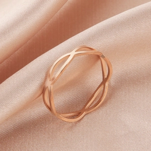 Detailopname van roségouden opengewerkte infinity-ring op elegante roze zijden achtergrond
