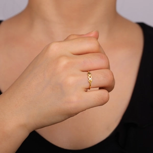 Close-up of heart-shaped gold ring worn on finger featuring a minimalist three-heart design