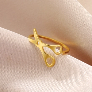 Anillo único de acero inoxidable dorado en forma de tijera sobre seda elegante
