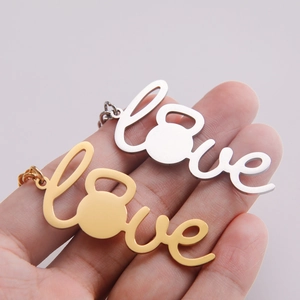Hand holding silver and gold kettlebell love heart pendant necklaces for fitness lovers