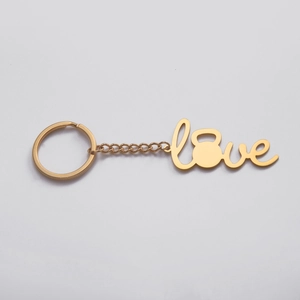 Detail eines goldenen 'love' Schlüsselanhängers mit Kettlebell-O und einer Stahlkette